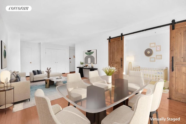 dining space featuring light hardwood / wood-style floors and a barn door