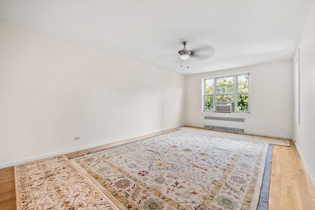 spare room with hardwood / wood-style floors, radiator heating unit, and ceiling fan