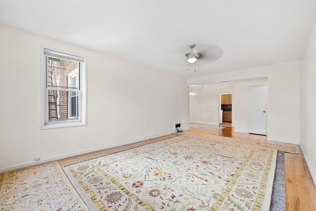 empty room featuring ceiling fan, baseboards, and wood finished floors