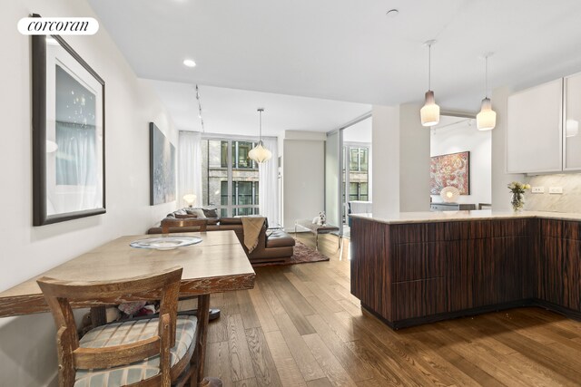 kitchen with hardwood / wood-style flooring, dark brown cabinetry, decorative backsplash, white cabinets, and decorative light fixtures