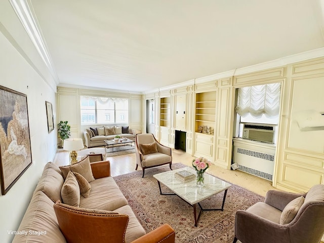 living area with built in shelves, crown molding, light wood-style flooring, radiator heating unit, and cooling unit