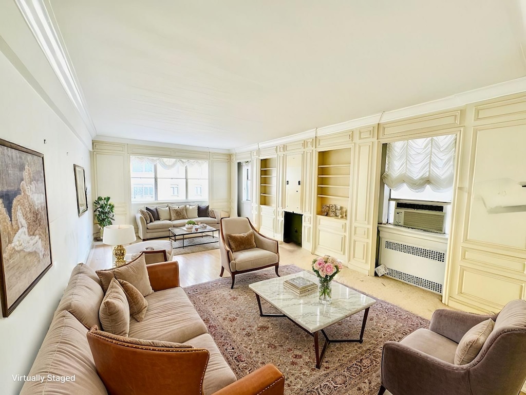 living area featuring cooling unit, built in shelves, radiator heating unit, crown molding, and light wood-type flooring