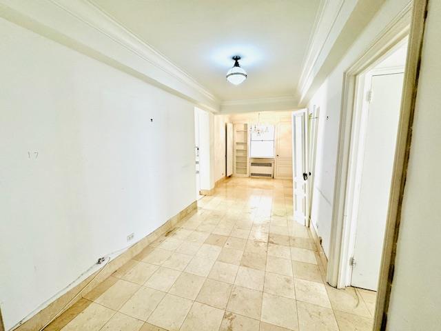 hall featuring a notable chandelier, baseboards, and crown molding