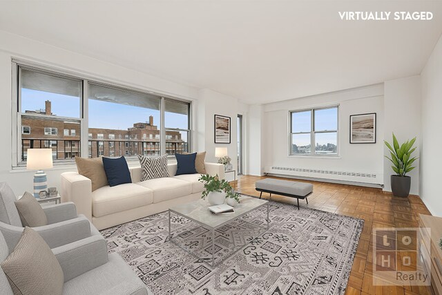 living room with a baseboard heating unit, a wealth of natural light, and parquet flooring