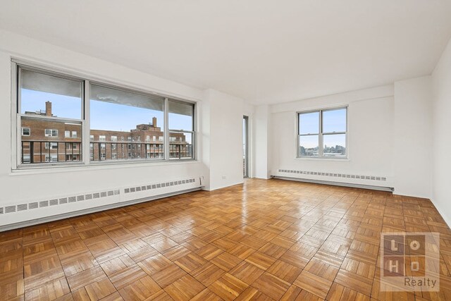 living room featuring parquet floors, a baseboard radiator, and a wealth of natural light