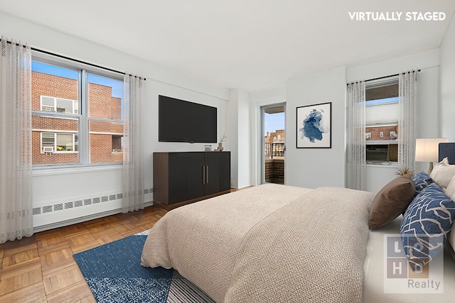 bedroom featuring multiple windows, parquet flooring, and radiator heating unit