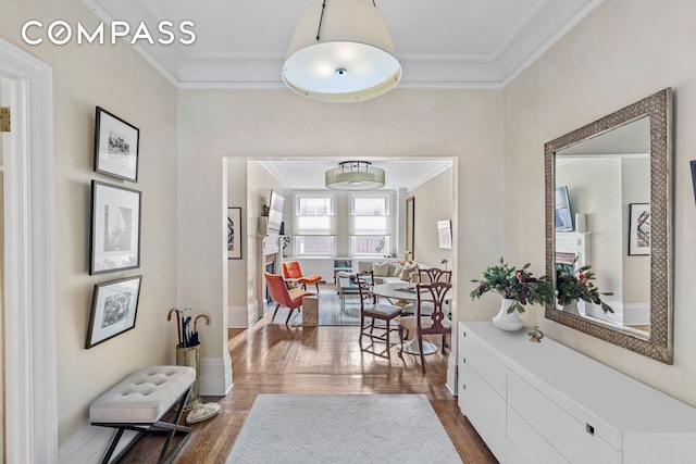 corridor featuring dark wood-style floors, crown molding, and baseboards