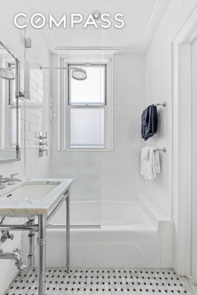 bathroom with tile walls, bathtub / shower combination, ornamental molding, a sink, and tile patterned flooring