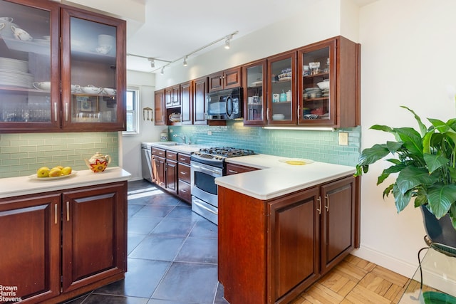 kitchen featuring glass insert cabinets, stainless steel appliances, light countertops, and a sink