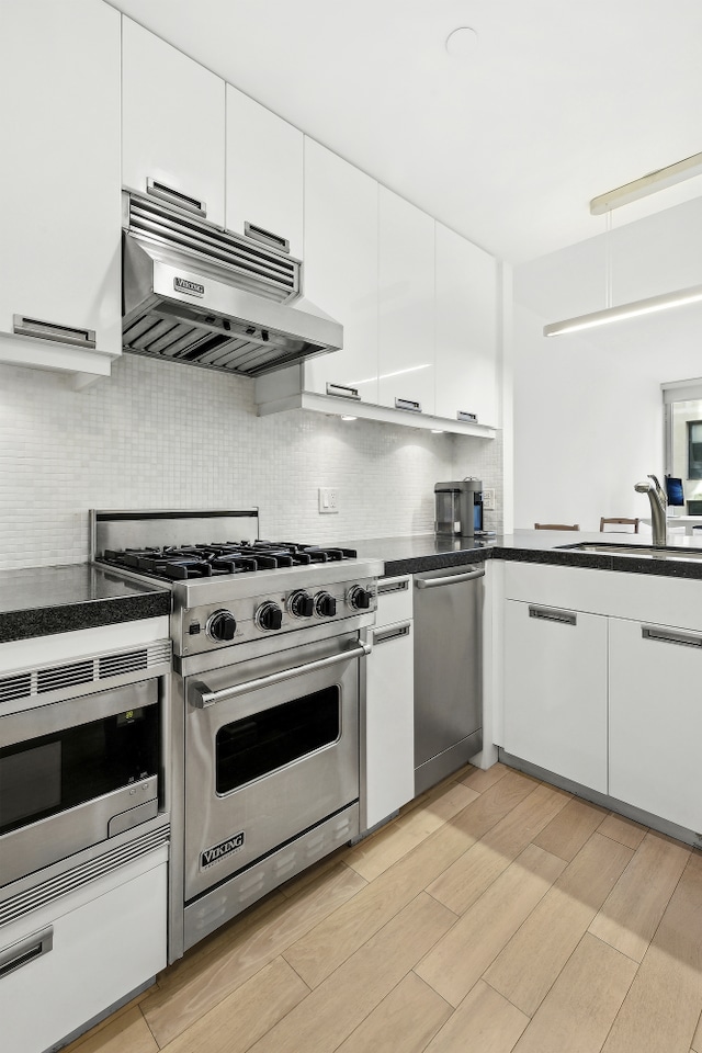 261 W 28th St Unit 3C, New York City, NY 10001 - kitchen with stainless steel appliances, under cabinet range hood, a sink, and white cabinetry