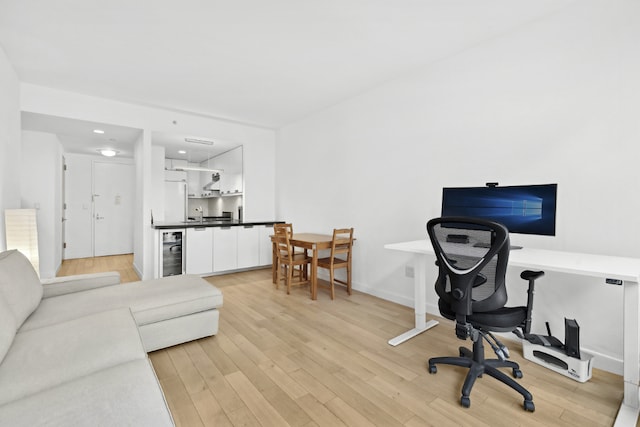 office featuring beverage cooler and light hardwood / wood-style flooring