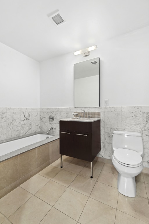 full bath featuring tile patterned flooring, toilet, visible vents, vanity, and tiled tub