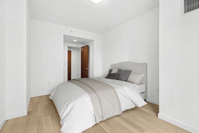 bedroom with visible vents, light wood-style flooring, and baseboards