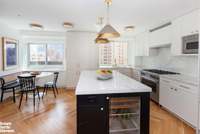 kitchen featuring beverage cooler, stainless steel appliances, a sink, white cabinets, and dark cabinetry