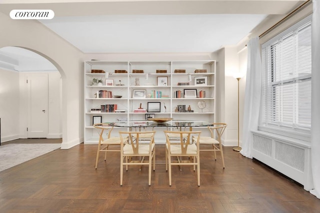 dining space featuring radiator heating unit and dark parquet floors