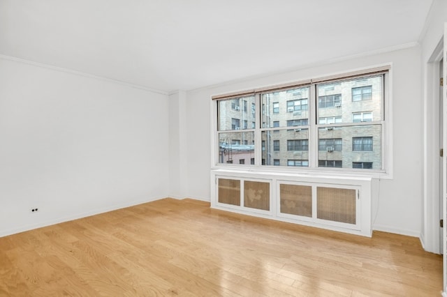 spare room with ornamental molding and light hardwood / wood-style flooring