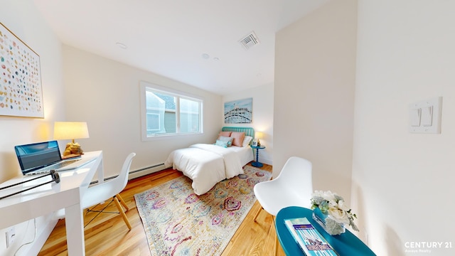 bedroom with a baseboard radiator, visible vents, and wood finished floors