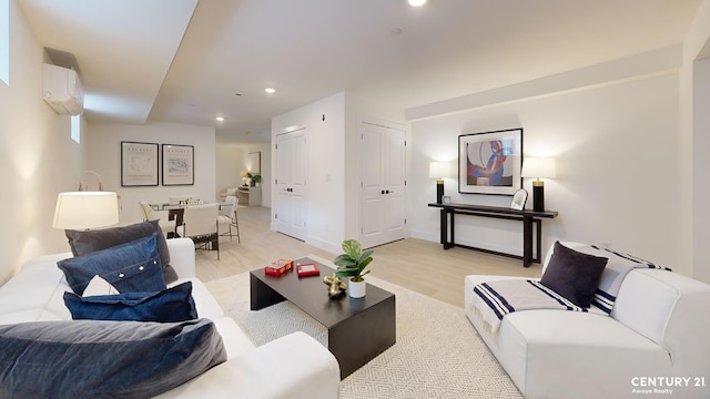 living area featuring an AC wall unit, light wood-style flooring, recessed lighting, and baseboards