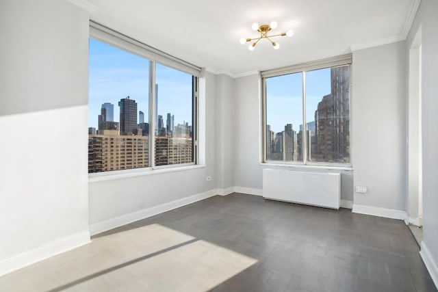 empty room featuring radiator, crown molding, and a notable chandelier