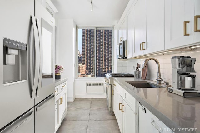 kitchen featuring sink, tasteful backsplash, dark stone counters, stainless steel appliances, and white cabinets