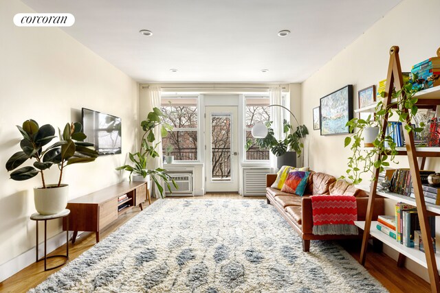 sitting room with hardwood / wood-style flooring and a wall unit AC