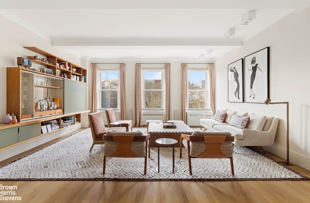 sitting room featuring crown molding, plenty of natural light, beamed ceiling, and wood finished floors