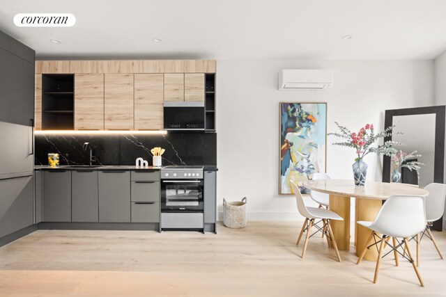 kitchen with gray cabinets, backsplash, light brown cabinets, light wood-type flooring, and stainless steel electric range