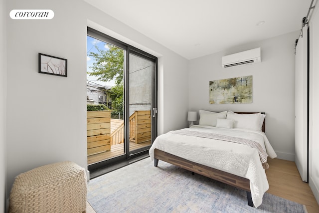 bedroom with hardwood / wood-style flooring, an AC wall unit, and access to outside