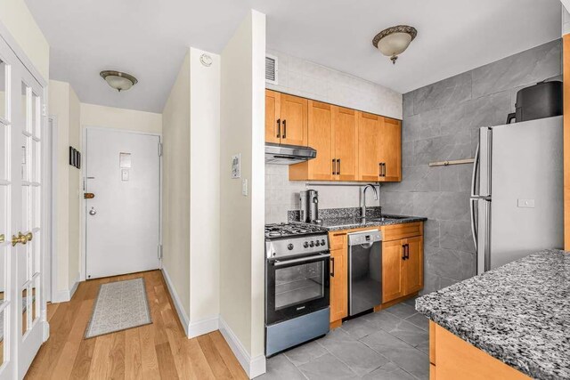 301 E 45th St Unit 10E, New York City, NY 10017 - kitchen featuring sink, dark stone countertops, tile walls, decorative backsplash, and stainless steel appliances