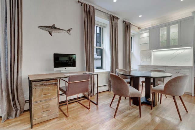 dining space with a baseboard radiator and light hardwood / wood-style flooring