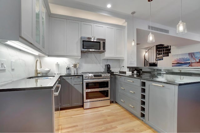 kitchen featuring pendant lighting, sink, gray cabinetry, stainless steel appliances, and kitchen peninsula