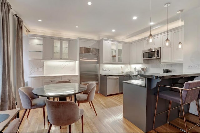 kitchen with pendant lighting, white cabinetry, stainless steel appliances, kitchen peninsula, and light wood-type flooring