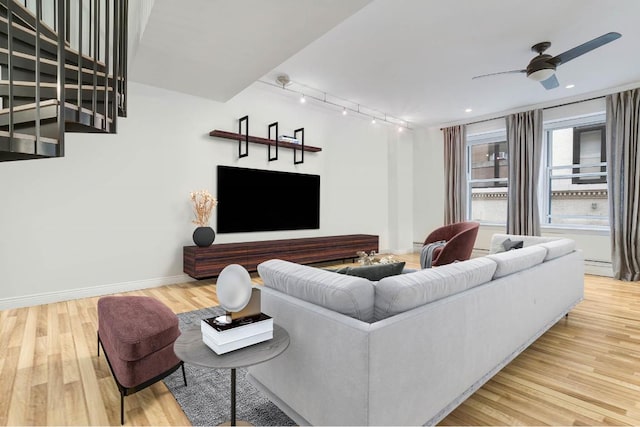 living room featuring hardwood / wood-style flooring, track lighting, ceiling fan, and baseboard heating