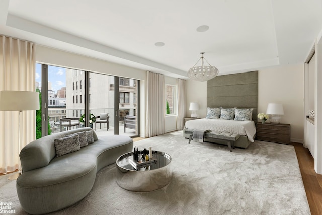 bedroom with an inviting chandelier, multiple windows, wood finished floors, and access to exterior