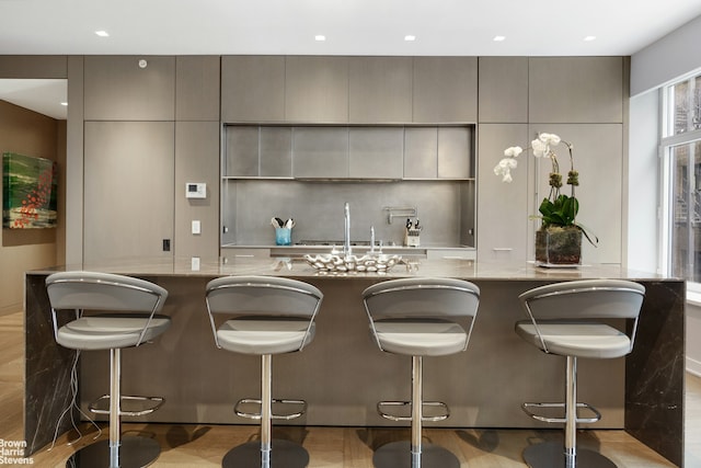 kitchen with a sink, gray cabinets, recessed lighting, and tasteful backsplash