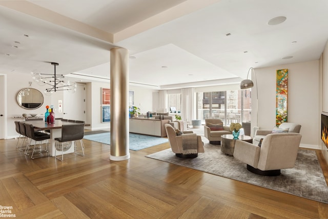 living area with ornate columns and a chandelier