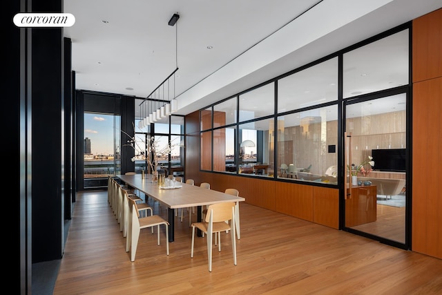 dining space with a wall of windows and light wood finished floors