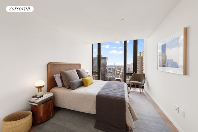 bedroom featuring visible vents, floor to ceiling windows, a city view, and baseboards