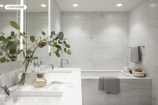 bathroom with a sink, double vanity, recessed lighting, and a bath