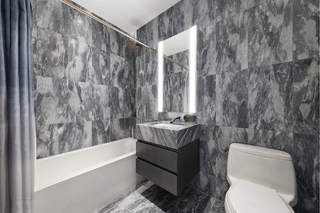 full bathroom with marble finish floor, toilet, vanity, tile walls, and  shower combination