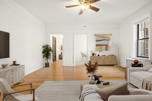 living area with light wood-type flooring, ceiling fan, and baseboards