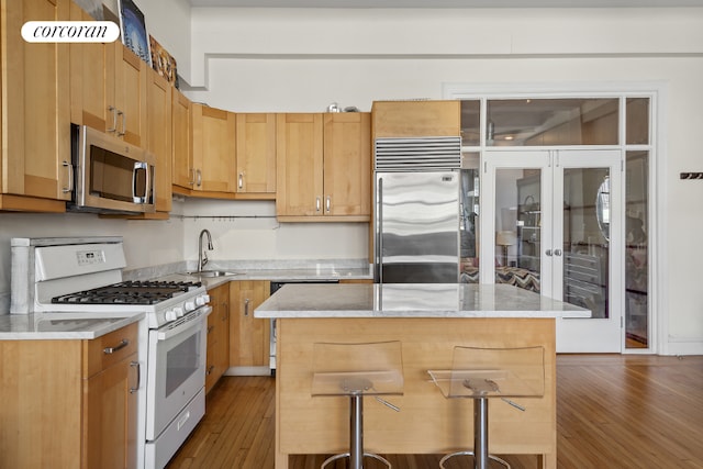 kitchen with sink, appliances with stainless steel finishes, a kitchen breakfast bar, dark hardwood / wood-style floors, and a kitchen island