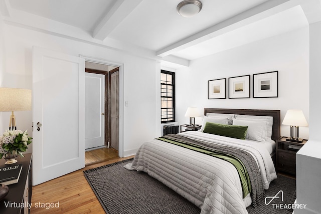 bedroom with light wood-type flooring and beam ceiling