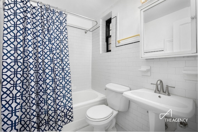 full bathroom with a sink, tile walls, toilet, and shower / bath combo with shower curtain