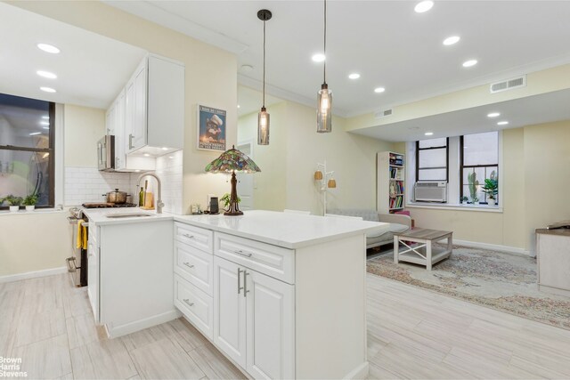 kitchen with sink, white cabinets, decorative backsplash, hanging light fixtures, and ornamental molding