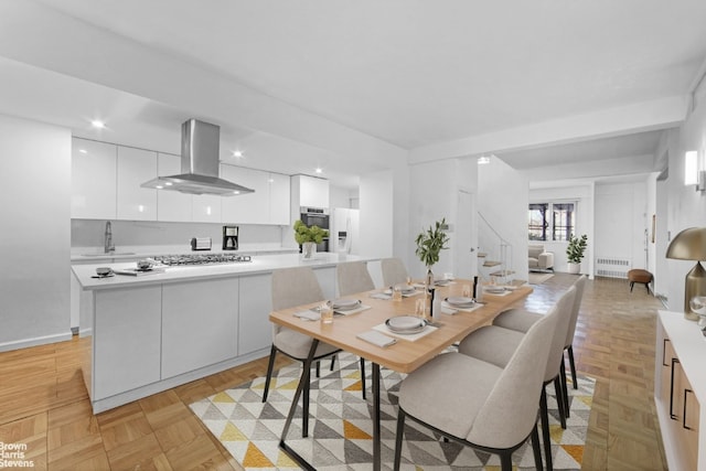 dining room featuring light parquet floors, radiator, and sink