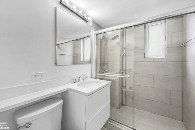 bathroom with toilet, a shower stall, and vanity