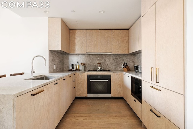 kitchen featuring light hardwood / wood-style flooring, black appliances, and light brown cabinets