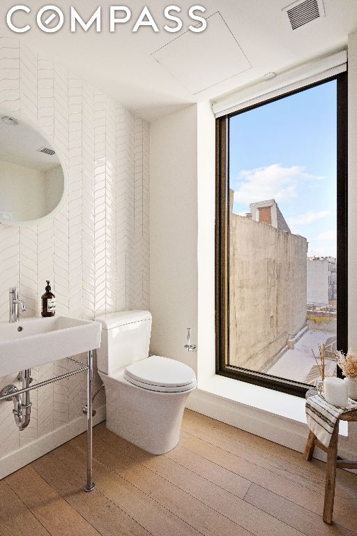 bathroom with hardwood / wood-style floors, a wealth of natural light, floor to ceiling windows, and toilet