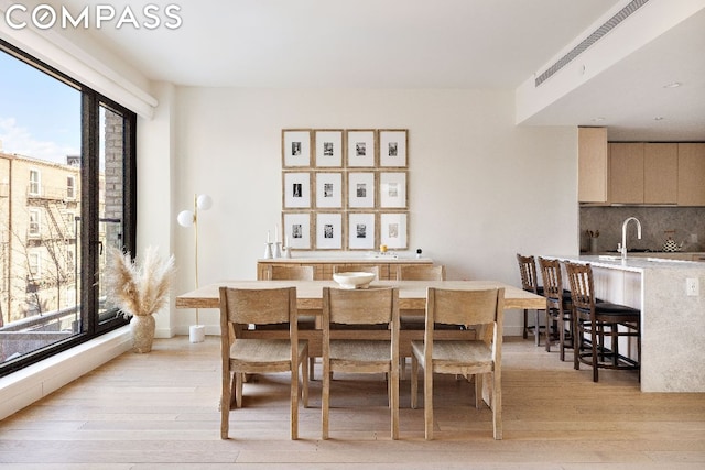 dining room featuring a healthy amount of sunlight, sink, and light hardwood / wood-style floors